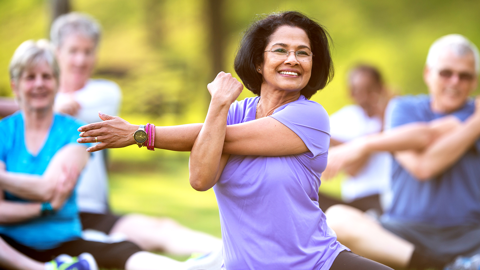 a woman leading a senior yoga class outside